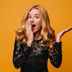 shocked fair haired girl posing yellow wall with mouth open surprised glamorous lady 1